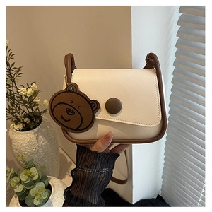 Vue détaillée du sac besace vintage crème avec bordures brunes et breloque petit ours