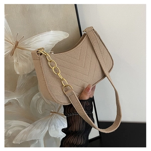 Detailed close-up of V-shaped quilted beige shoulder bag with golden chain strap
