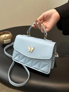 Light blue quilted crossbody bag with golden butterfly clasp and elegant top handle