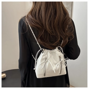 Detailed back view of a white leather drawstring bucket backpack with silver metal chains
