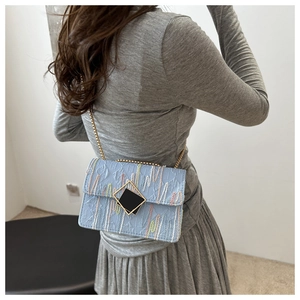Detail of light blue crossbody bag with textured stripes and gold chain strap