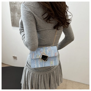 Detail of light blue checkered crossbody bag with gold chain strap on a model