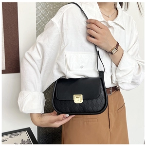Close-up of black matte shoulder bag with quilted texture and gold lock on white shirt