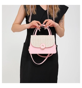 Detail of pink leather and beige woven straw handbag with a golden circular metal buckle