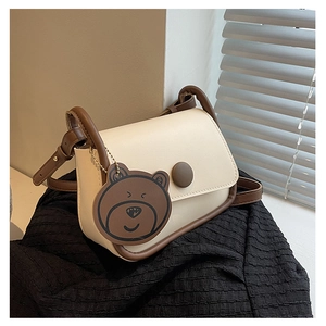 Détail du sac à main crème avec bordure marron et breloque ours en peluche mignonne