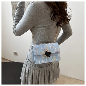 Detail of light blue crossbody bag with rainbow embroidery and gold chain strap