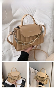 Detail of khaki crossbody bag featuring vertical quilting and decorative acrylic chain