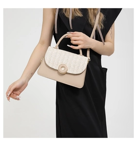 Detail of a woven flap crossbody bag with V-shaped texture on a model in black dress