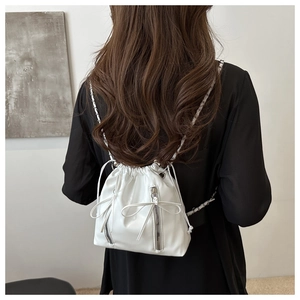 Detail of white PU leather bucket backpack featuring chain straps and bow decoration