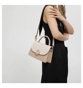 Detail of beige crossbody bag with woven texture flap and round metallic buckle on model