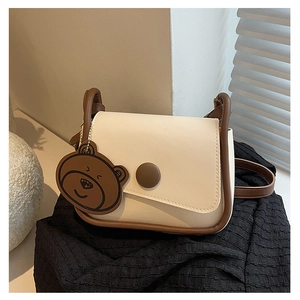 Vue détaillée du sac besace crème avec bordure marron et pendentif ours mignon