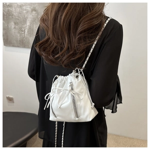 Detail of white drawstring bucket bag with bow and silver chain on model back