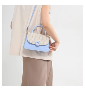 Detailed view of light blue crossbody bag featuring beige woven texture and round buckle