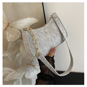 Detail of gray felt baguette bag featuring chunky gold chain and thick shoulder strap