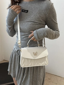 Elegante weiße Umhängetasche mit Steppung und goldener Schmetterlingsschließe am Modell