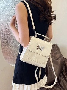 Minimalist white faux leather mini backpack featuring liquid silver butterfly hardware
