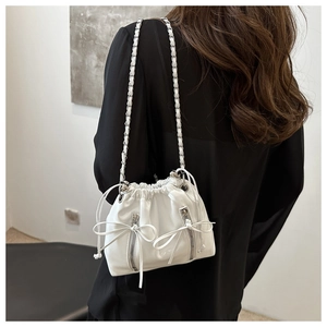 Detail of white drawstring bucket backpack with chain strap and bow zipper on model