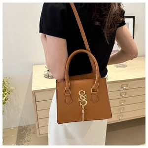 Detailed view of brown faux leather handbag with gold SOS logo and metal chain tassel