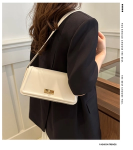 Detail of minimalist cream crossbody bag featuring a golden square twist lock buckle