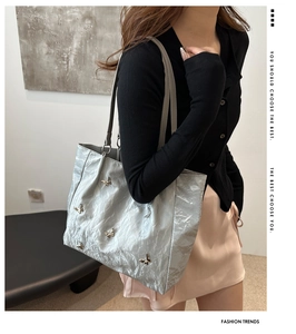Close-up of metallic silver tote bag with butterfly charms worn by a model