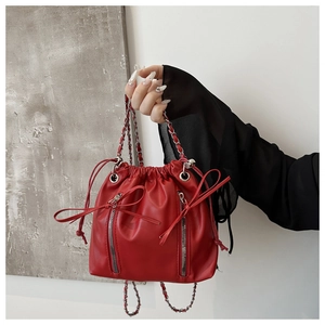 Detail of red bucket backpack with silver chains and bow tie zipper accents