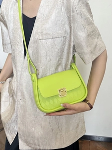 Neon green quilted crossbody bag with gold buckle shown on a stylish model in a suit
