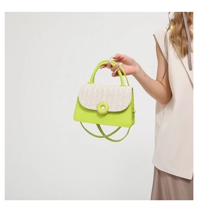 Detail of lime green leather handbag with woven straw flap and circular buckle accent