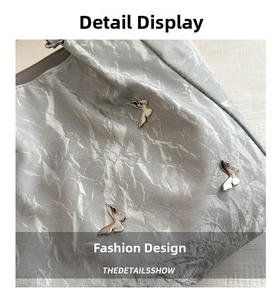 Macro shot of silver pleated fabric and metallic butterfly accents on a stylish tote bag