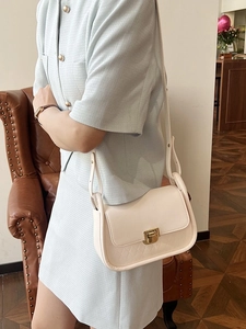 Chic cream-colored quilted shoulder bag with gold hardware worn by a model