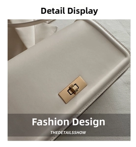 Detail shot of a cream leather crossbody bag featuring a gold rectangular twist lock