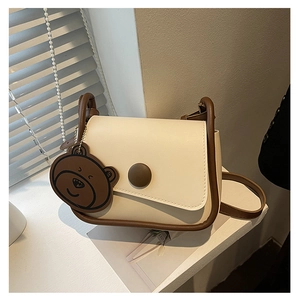 Détail du sac à selle minimaliste avec bordure contrastée et porte-clés ours mignon