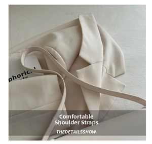 Close-up of the wide comfortable shoulder strap and cream twill fabric of the handbag