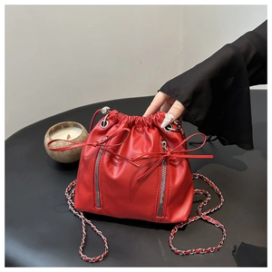 Detail of red bucket backpack with drawstring bows and silver chain strap for women