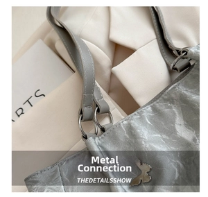 Macro detail of silver bucket bag with pleated leather texture and butterfly metal emblem