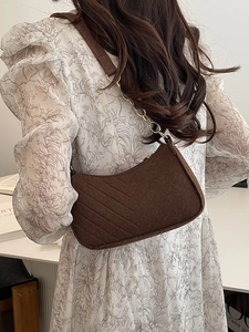 Brown quilted wool shoulder bag with gold chain strap shown on a model in a summer dress