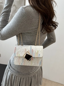 White mini crossbody bag with colorful stripes and chain strap on female model