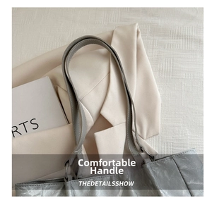 Macro detail of grey pleated bucket bag handle and soft leather texture on minimalist background