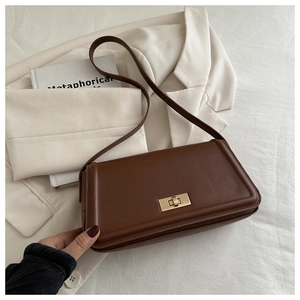Detail of a brown leather shoulder bag with a gold rectangular twist-lock and shoulder strap