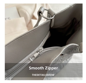 Macro shot of smooth silver metal zipper and dark brown lining on a gray tote bag