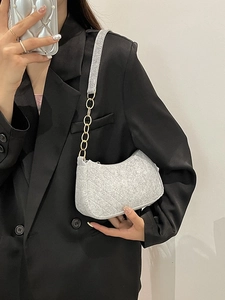 Chic grey quilted felt shoulder bag with golden chain strap worn by a woman in a suit