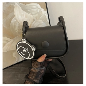 Détail du sac besace en cuir PU noir avec boucle ronde et charmant pendentif ours