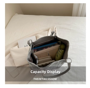 Macro view of large grey tote bag showing internal capacity for books and umbrella