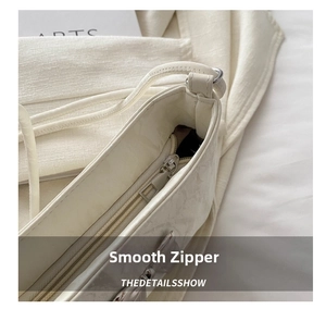 Close-up of smooth zipper closure on off-white pleated underarm shoulder bag