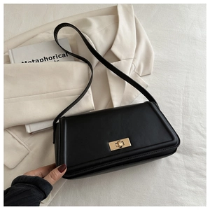 Detail of minimalist black leather shoulder bag with gold metal twist lock and fine stitching