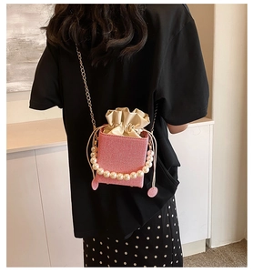 Pink woven box bag with pearl handle and chain strap shown on model for size scale
