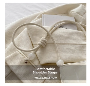 Detail of a creamy white woven leather shoulder strap featuring clear resin bead accents