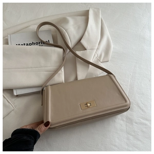Close-up of beige leather tote bag with gold metal lock and shoulder strap detail