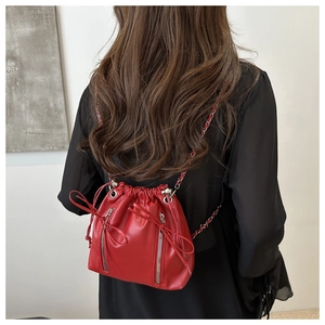 Detail of red drawstring bucket backpack featuring vertical zippers and chain straps