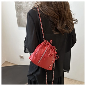 Detailed back view of a red mini drawstring bucket bag with silver zippers and chain strap