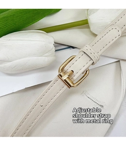 Detail of adjustable off-white leather strap with gold metal buckle on a shoulder bag